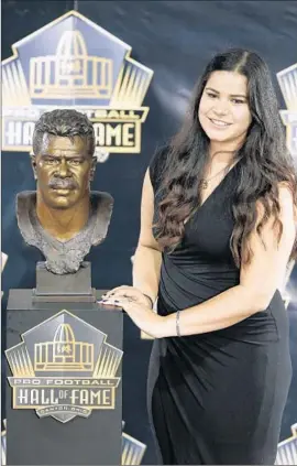  ?? Joe Robbins Getty Images ?? SYDNEY SEAU STANDS with a bust of her father, Junior Seau. Though not allowed to officially speak in his place, she paid tribute to him in moving remarks.