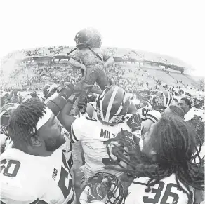  ?? MIKE CARTER/USA TODAY SPORTS ?? Michigan players carry the Paul Bunyon Trophy out of Spartan Stadium after their 21-7 victory against Michigan State.