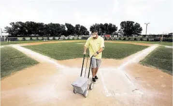  ?? Thomas B. Shea photos ?? Byron Oujes limes the field on Wednesday for games — without showers — at the Dad’s Club in Pearland.