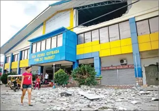  ?? MANMAN DEJETO/AFP ?? A resident walks past debris from a partially damaged building on the southern Philippine island of Mindanao on Thursday after a 6.4 earthquake struck the night before.