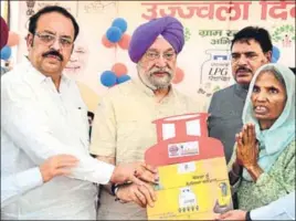  ?? SAMEER SEHGAL/HT ?? ■ Union minister of state for housing and urban affairs Hardeep Singh Puri (centre) and BJP Punjab state president Shwait Malik (left) giving a gas connection to a woman under the Pradhan Mantri Ujjwala Yojana at Mudhal village in Amritsar on Thursday.