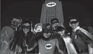  ?? The Associated Press ?? TRIBUTE: Fans dressed as characters from “Batman” pose in front of a Bat-Signal projected onto City Hall following a tribute to “Batman” star Adam West on Thursday in Los Angeles.