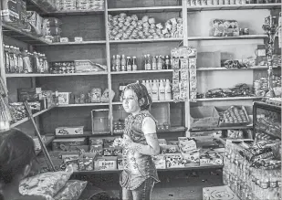  ??  ?? Nour Lazem, 10, who lost 16 members of her family in a suicide bombing, looks out at a shop in east Mosul.