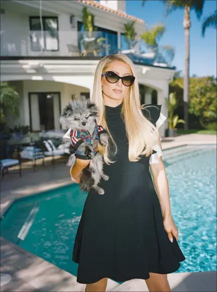  ?? ROSIE MARKS / THE NEW YORK TIMES ?? Paris Hilton is seen Tuesday with one of her dogs at her home in Beverly Hills, Calif. In addition to the f lagship podcast “This Is Paris,” Hilton’s new deal with iheartmedi­a calls for the creation of six other shows over the next three years.