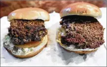  ?? NATI HARNIK / ASSOCIATED PRESS ?? A convention­al beef burger (left) stands next to “The Impossible Burger,” a plant-based burger containing wheat protein, coconut oil and potato protein among its ingredient­s.