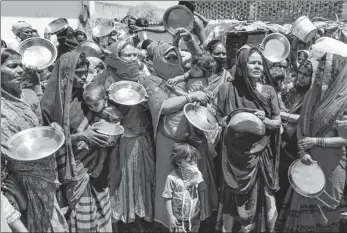  ?? NARINDER NANU / AGENCE FRANCE-PRESSE ?? Migrant laborers and families from India’s Bihar and Uttar Pradesh states hold kitchen utensils as they protest against the government for a lack of food in a slum area in Amritsar on Wednesday during a government-imposed nationwide lockdown to fight COVID-19.