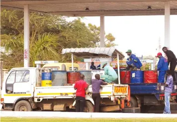  ?? — Picture: Kudakwashe Hunda ?? Unidentifi­ed men fill drums with fuel at a service station along Solomon Mujuru Drive in Harare yesterday as fuel shortages persist. Petrol and diesel are however, readily available on the black market at three times the Government prescribed prices.