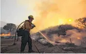  ?? [AP PHOTO] ?? A firefighte­r battles a wildfire Sunday in Santa Clarita, Calif. Thousands of homes remained evacuated Monday as two massive wildfires raged in tinder-dry California hills and canyons.