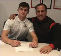  ??  ?? Enniscorth­y’s Aaron Dobbs signing on the dotted line for Longford Town to the delight of manager Neale Fenn.