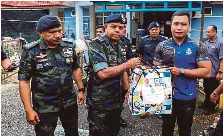  ?? NSTP PIX BY NIK ABDULLAH NIK OMAR ?? Deputy Inspector-General of Police Datuk Seri Ayob Khan Mydin Pitchay handing over flood aid to a policeman in Tumpat yesterday.
