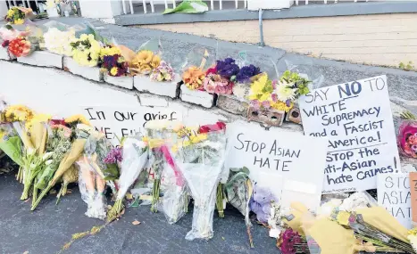  ?? CANDICE CHOI/AP ?? Flowers, candles and signs are displayed at a makeshift memorial Friday in Atlanta, where eight people were killed in spa businesses earlier this week. Seven of those killed were women and six were of Asian descent.