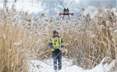  ?? FOTOS: THOMAS WARNACK ?? Václan Demeter bringt mit einer Drohne die Vogelabwei­ser an der Freileitun­g über dem Vogelsee in Zielfingen an.
