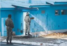  ??  ?? Three blue huts sit on the border between North and South Korea, with soldiers from both sides guarding the Joint Security Area. The South Korean soldiers stand partly behind the corner of the buildings in case shooting breaks out.