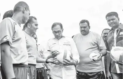  ??  ?? ANWAR menurunkan tanda tangannya pada sebuah bola sempena Perlawanan Tujuh Sebelah Piala YB Ravi 2018 di Padang Merdeka, pada Ahad. -Gambar Bernama