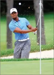  ??  ?? Tiger Woods blasts out of the bunker on the fifth hole during the second round at Firestone on Friday.