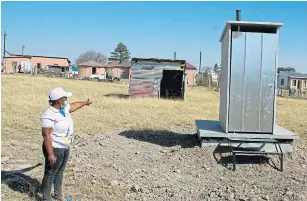  ??  ?? MIDDLE OF NOWHERE: Nyameka Mongezi, of the African Transforma­tion Movement, reveals a toilet that has been built on an empty plot.