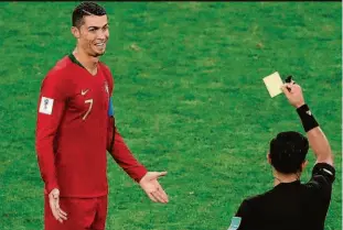  ??  ?? O árbitro paraguaio Enrique Cáceres dá um cartão amarelo a Cristiano Ronaldo após consultar o monitor ao lado do campo; juiz havia sido avisado pelo VAR