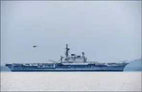  ??  ?? Indian Navy’s decommissi­oned aircraft carrier INS Viraat is towed by boats as a helicopter hovers above on the ship’s final journey to the Alang Ship breaking yard in Gujarat, from the naval dockyard in Mumbai yesterday.