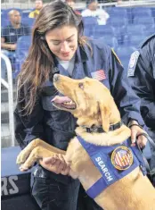  ?? DAVID SANTIAGO dsantiago@miamiheral­d.com ?? South Florida Urban Search and Rescue Team member Veronica Cordoba plays with her partner Jax before Friday’s game, at which first responders were honored.