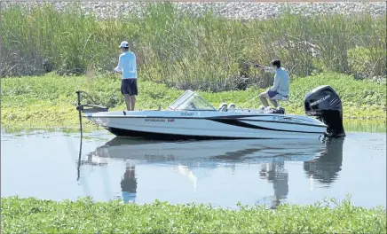  ?? SUSAN TRIPP POLLARD — STAFF ARCHIVES ?? Along the calm waters of the California Delta, two men try their luck fishing from a boat at Holland Tract.