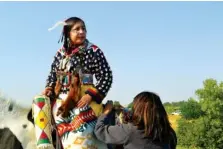  ?? THE ASSOCIATED PRESS ?? Julia Brien, left, prepares on Thursday for the Crow Fair parade in Crow Agency, Mont. For the Crow Tribe, the eclipse coincides with the Parade Dance at the annual Crow fair, marking the tribe’s new year.