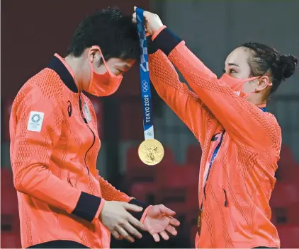  ?? JUNG YEON-JE AGENCE FRANCE-PRESSE ?? Le Japonais Jun Mizutani reçoit la médaille d’or de sa coéquipère Mima Ito au haut du podium de tennis de table à Tokyo, lundi.