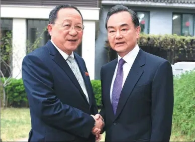  ?? WANG ZHUANGFEI / CHINA DAILY ?? State Councilor and Foreign Minister Wang Yi (right) shakes hands with Ri Yong-ho, foreign minister of the Democratic People’s Republic of Korea, on Tuesday in Beijing.