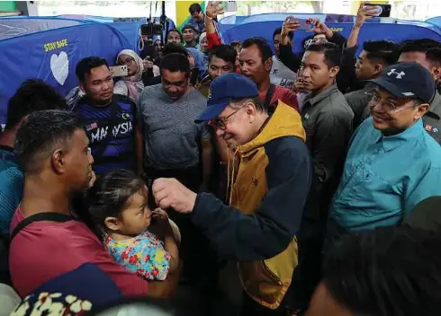  ?? - Gambar NSTP/GHAZALI KORI ?? ANWAR menyantuni manga banjir di PPS Sekolah Kebangsaan Mangkok, Setiu, semalam. Turut sama, Dr Ahmad Samsuri (kanan).