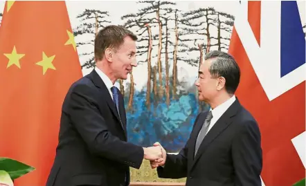  ?? — Reuters ?? Working together: Hunt shaking hands with Wang after a joint news conference at the Diaoyutai State Guesthouse in Beijing.