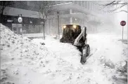  ?? KATHERINE TAYLOR / THE NEW YORK TIMES ?? A snow plow moves snow out of a roadway during a storm Saturday in Boston.