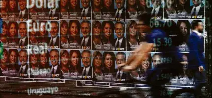  ?? Ricardo Moraes - 25.out.19/Reuters ?? Painel com cotação reflete cartazes com os rostos de Alberto Fernández e Cristina Kirchner