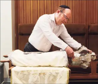  ??  ?? Rabbi Daniel Cohen prepares the Torah, covered in white in honor of the High Holy Days, at Temple Agudath Sholom in Stamford on Sunday.