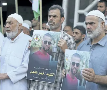  ?? ADEL HANA/THE ASSOCIATED PRESS ?? Islamic Jihad supporters hold pictures of Nimr Jamal, who opened fire Tuesday at the entrance of the Har Adar Israeli settlement, killing three Israeli security workers before being killed himself, at a rally in Gaza City.
