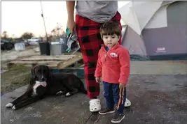  ?? GERALD HERBERT — THE ASSOCIATED PRESS ?? Katelyn Smith stands with her 1-year-old son Ricky Trahan III as their family lives in a camper and tents where their home was destroyed in Lake Charles, La., Dec. 4.