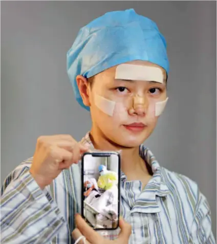  ??  ?? March 3, 2020: Nurse Xu Jian from a hospital in Fujian Province shows on her mobile phone how she takes care of her patient. By then, she had been helping save lives in Wuhan Union Hospital of China for more than a month. by Li Ge