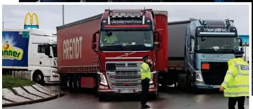  ??  ?? Gridlock: HGVs block a roundabout outside the disused airfield in protest at the lack of tests. Right, hauliers confront officers after being refused Covid checks