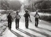  ??  ?? Farm labourers in Horsham, Sussex, heading home with their tools after a 17-hour shift in July 1947