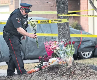 ?? RICHARD LAUTENS/TORONTO STAR ?? A Durham police officer delivers flowers for neighbours and supporters, who were not allowed to cross the police lines in Ajax.