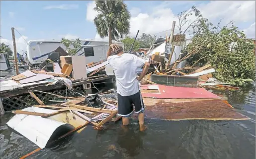  ?? Gerald Herbert/Associated Press ?? Larry Dimas walks around his destroyed trailer, which he had rented to others, in the aftermath of Hurricane Irma on Monday in Immokalee, Fla. His tenants evacuated and no one was inside when it was destroyed.