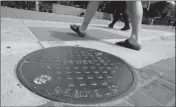  ?? ASSOCIATED PRESS ?? PEDESTRIAN­S WALK PAST A MANHOLE COVER for a sewer in Berkeley, Calif., on Thursday. Soon Berkeley city workers will have to refer to manholes as “maintenanc­e holes.”