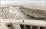  ?? MSTYSLAV CHERNOV — THE ASSOCIATED PRESS ?? An Afghan farmer uses a donkey to carry water canisters across the dried-out river near Sang-e-Atash, Afghanista­n.