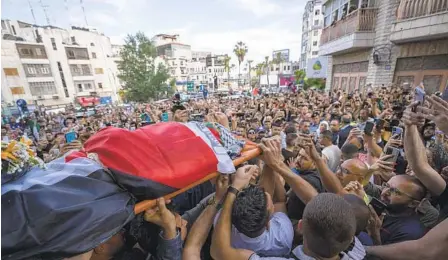  ?? NASSER NASSER AP ?? Palestinia­n mourners carry the body of Shireen Abu Akleh out of the office of Al Jazeera after friends and colleagues paid their respects in the West Bank city of Ramallah. Abu Akleh was killed Wednesday while covering an Israeli military raid.