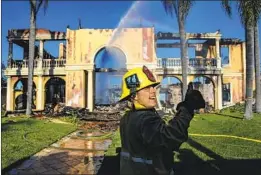  ?? ?? ORANGE COUNTY firefighte­r Daniel Couts directs a stream of water at a home in the community of Coronado Pointe. At least 20 homes were destroyed.