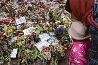  ?? Sean Gallup/Getty Images ?? A woman and child look at messages at a makeshift memorial to Russian opposition figure Alexei Navalny on Saturday in front of the Russian Embassy in Berlin.