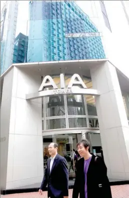  ?? BLOOMBERG ?? Two men walk past American Internatio­nal Group Inc’s AIA Tower in Hong Kong.