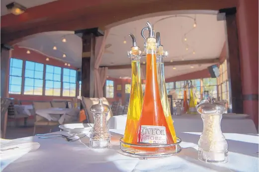  ?? EDDIE MOORE/JOURNAL ?? Olive oil and other condiments stand ready for use on a table in the upstairs dining room at Pranzo Italian Grill.