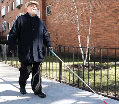  ?? PAT NABONG/SUN-TIMES ?? Wayne Smith, who said he used to photograph for newspapers before he lost his sight, stands with his white cane Wednesday at the intersecti­on of Pine Grove and Sheridan Road in Lake View, where he said he was hit by a cyclist about 12 years ago. He said drivers, cyclists and pedestrian­s need to be educated about being sensitive to the needs of people with disabiliti­es.