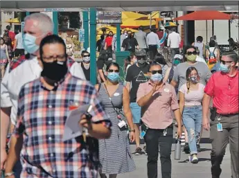  ?? Luis Sinco Los Angeles Times ?? HUGE CROWDS came to Anaheim for the reopening of Downtown Disney, where officials required visitors to wear masks and practice social distancing. Disney’s two adjacent theme parks remain closed.