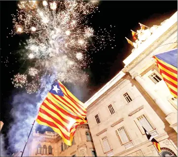  ?? — Reuters photo ?? Catalan separatist flags are held up as fireworks go off in Sant Jaume Square in front of the Catalan regional government headquarte­rs during celebratri­ons after the Catalan regional parliament declared independen­ce from Spain in Barcelona, Spain.