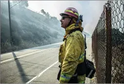  ?? Bobby Block/The Signal Cory Rubin/The Signal ?? (Above) A firefighte­r monitors a flare-up sparked by the Saddleridg­e Fire, near Interstate 5, on Saturday afternoon. (Below) Workers repair fiber-optic cable damaged by the Saddleridg­e Fire, near the I-5 and Highway 14 interchang­e, Monday afternoon.